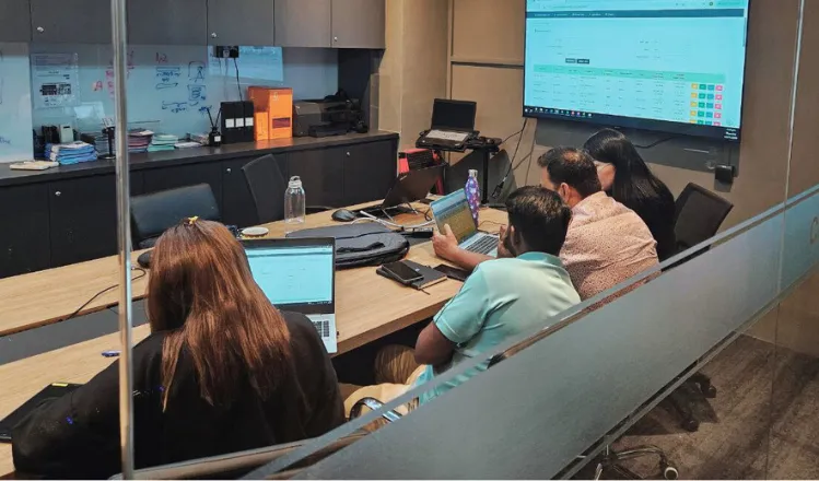 Team reviewing the InSight™ Servicing dashboard on laptops and a wall screen